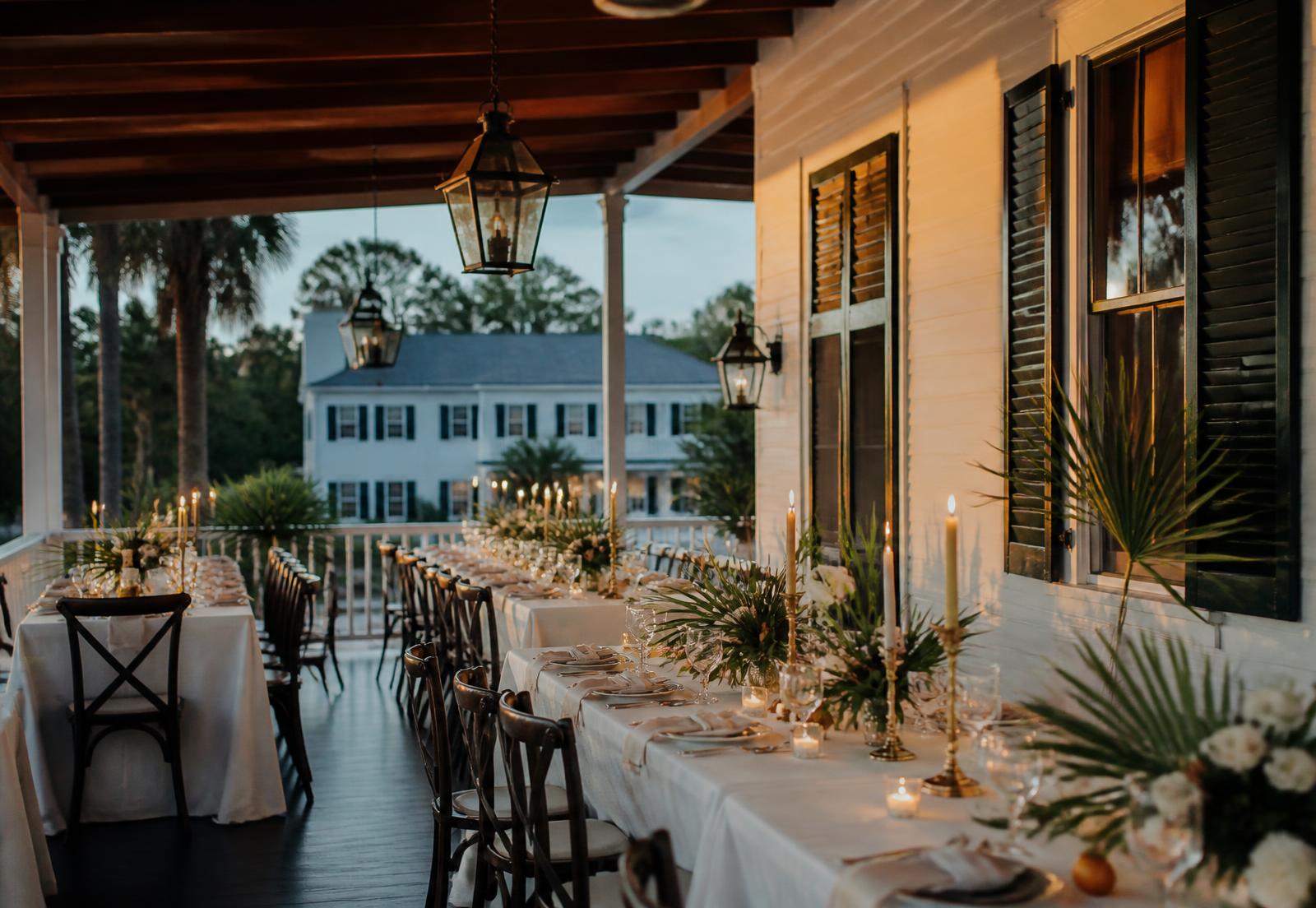 Two long linen tables set for dinner on a covered estate terrace